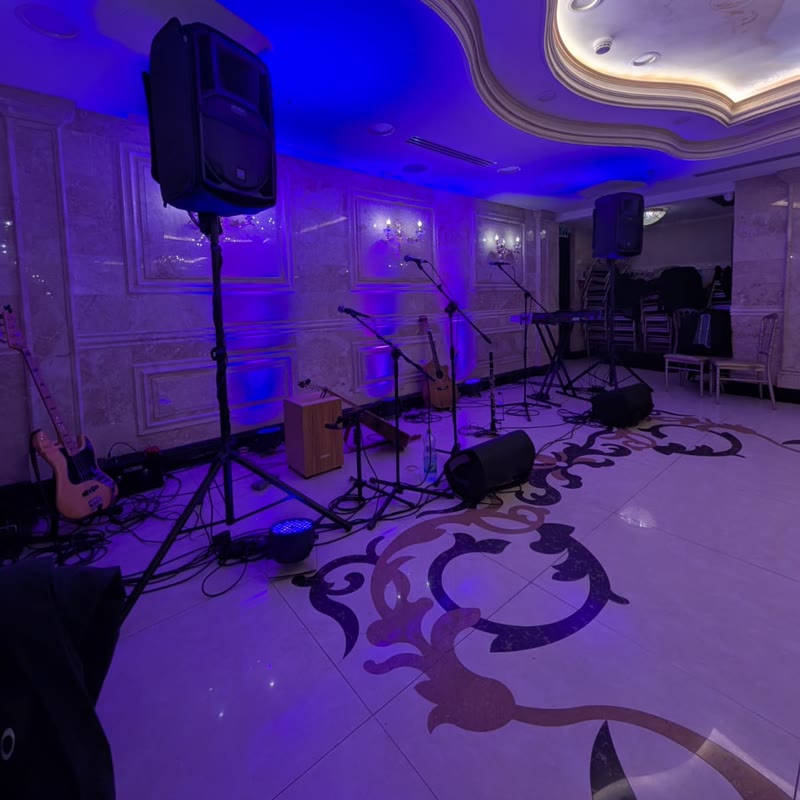 Bruzo speakers, monitors, and mics set up on a dance floor lit in blue and purple